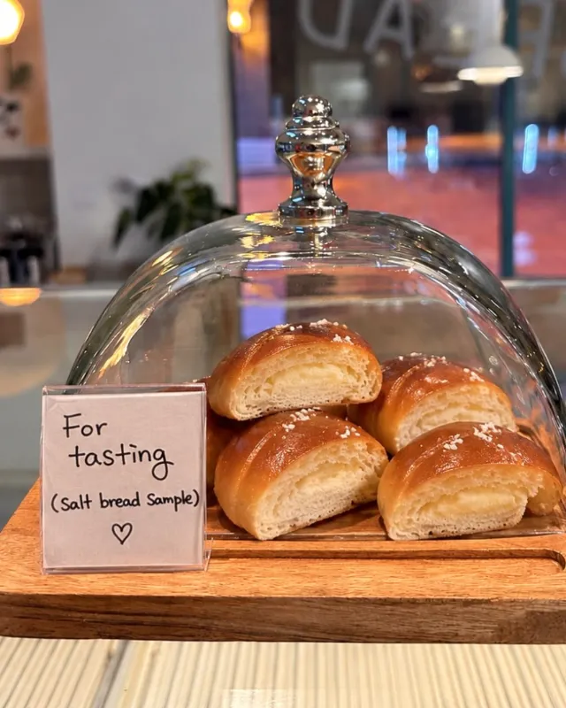 Original salt breads under a glass dome on the counter, with a handwritten “For tasting” card